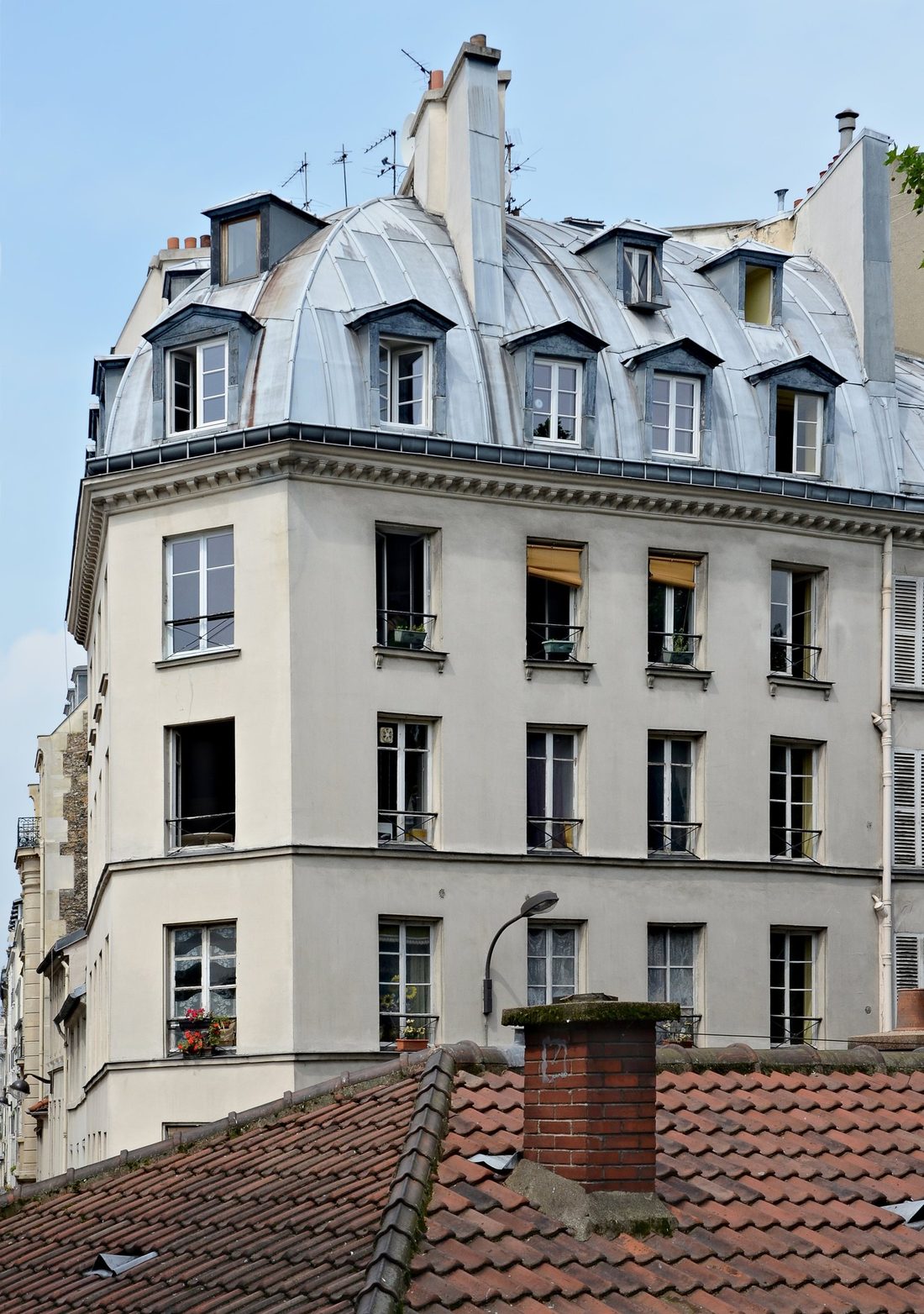 Immeuble d'angle parisien : mansarde en zinc au-dessus d'un toit de tuiles anciennes, rue des Vinaigriers